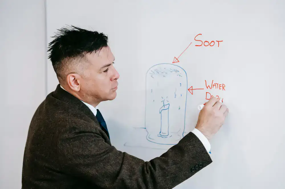 A language instructor writing on a whiteboard and explaining a concept