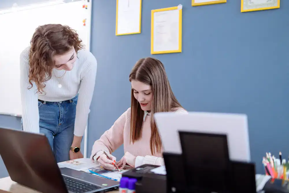 A teacher helping a student review language materials in a bright, modern learning space